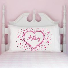 a white bed topped with a pink heart pillow