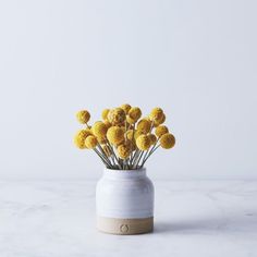 a white vase with yellow flowers in it