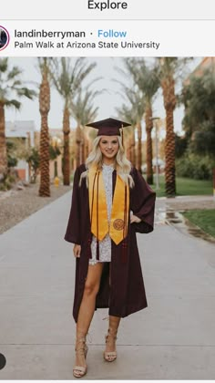 a woman in a graduation gown and cap is standing on the sidewalk with palm trees