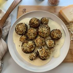 a white plate topped with stuffed mushrooms covered in cheese and sauce next to other food items