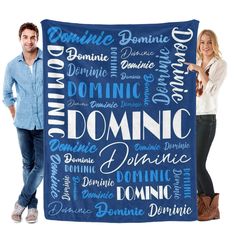 two people standing next to a blue and white blanket with words written all over it