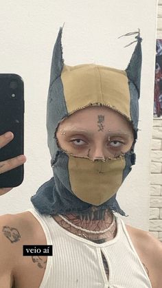 a man wearing a batman mask holding up his cell phone to take a selfie