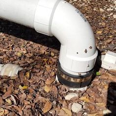 a white pipe laying on the ground next to leaves