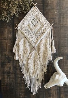 the wall hanging is made with macrame and tassels, along with a cow skull