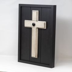 a wooden cross mounted to the side of a black door with a button on it