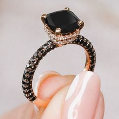 a close up of a person's hand holding a black and white diamond ring