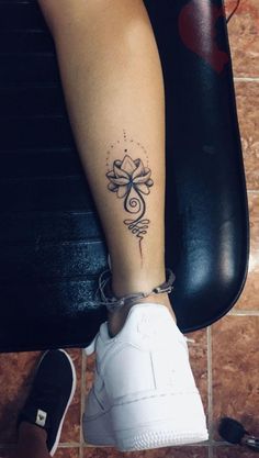 a woman's foot with a tattoo on her left leg and a cross in the middle