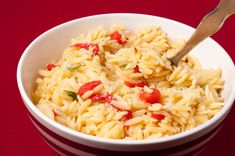 a white bowl filled with pasta on top of a red table