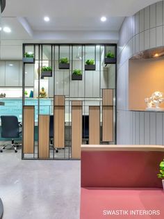 an office with glass partitions and plants in the window boxes on the desk area