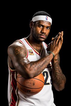 a man holding a basketball in his right hand and wearing a headband with tattoos on it