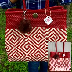 a person holding a red and white bag with a pom - pom on it