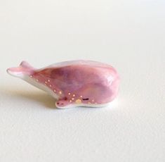 a figurine of a pink whale on a white surface