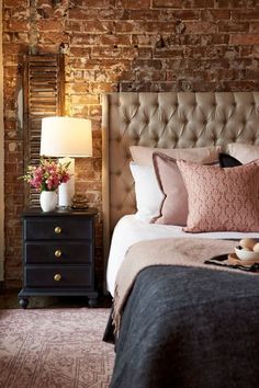 a bedroom with brick walls and a bed in the middle, along with a nightstand that has flowers on it