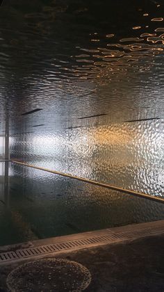 an empty parking garage with rain on the floor and water running down the side wall