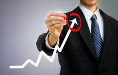 a man in a suit and tie holding up a marker with an upward arrow on it