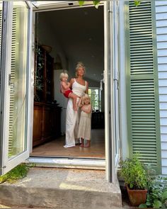 a woman and two children standing in an open door