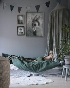 a person laying in a bed with a green blanket on it and pictures hanging above the bed