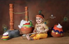 a baby sitting on the ground in front of some potted plants and other items