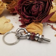 a close up of a flower on a keychain with flowers in the background