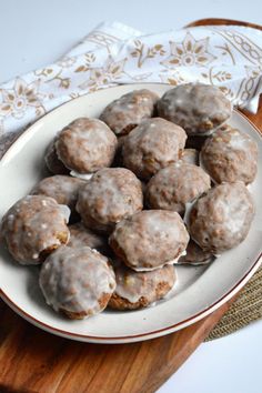 a white plate topped with donuts on top of a wooden table next to a napkin