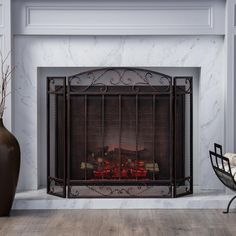 a fireplace with a fire in it next to a chair and vase on the floor