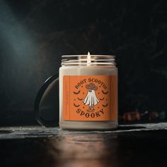 an orange and white candle sitting on top of a table next to a black mug