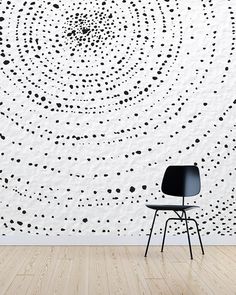 a chair sitting in front of a wall with black dots on it and a white background