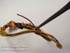 a pair of scissors is hooked up to a cord that has been wrapped in gold and red beads