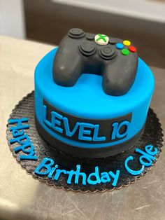 a blue birthday cake with a video game controller on it's top and the words level 10