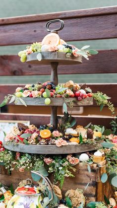 a three tiered tray with fruit and flowers on it