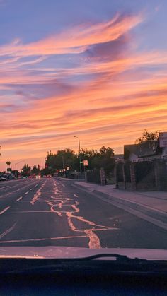 the sun is setting over an empty street with no cars or people on it, and there are clouds in the sky