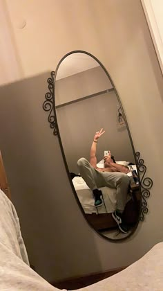 a man taking a selfie in a mirror on the wall next to a bed