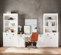 an office with white bookcases and leather chair