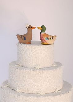 two wooden ducks sitting on top of a wedding cake