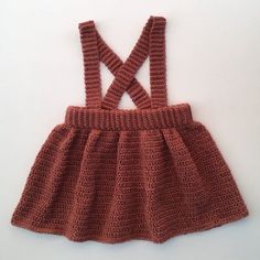 a crocheted baby dress with suspenders on the bottom and straps at the waist