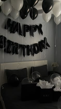 black and white balloons are hanging from the ceiling in front of a bed with a birthday sign on it