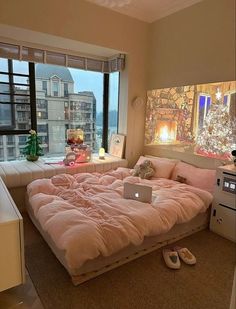 a bedroom with a large bed and a laptop on the floor in front of a window