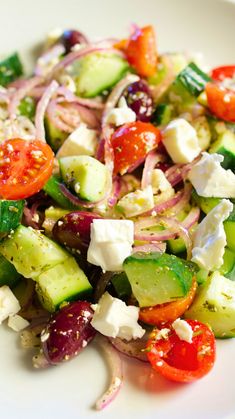 a salad with cucumbers, tomatoes, onions and feta cheese on it