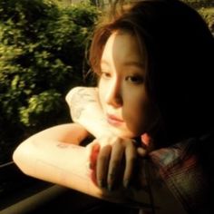 a young woman leaning on a window sill with her arm resting on the windowsill