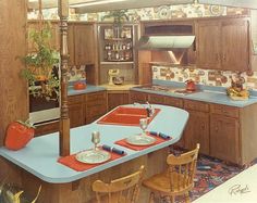 an old fashioned kitchen with wooden cabinets and blue counter tops, including two ovens