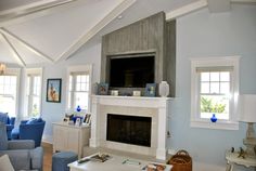 a living room filled with furniture and a flat screen tv mounted on the wall above a fireplace