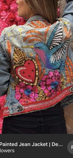 a woman wearing a jean jacket with flowers painted on it and the back of her jacket