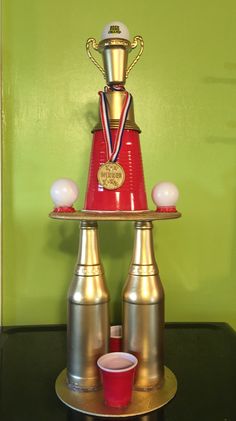 a red and gold trophy sitting on top of a metal tray next to two cups