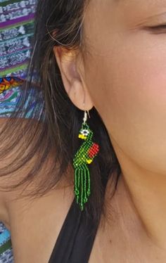 Expertly crafted with intricate beadwork, these Large Beaded Quetzal Earrings embody the beauty and culture of Guatemala. The dainty green and red design adds a stunning touch to any outfit, making them a unique and elegant accessory for any occasion. Embrace the unparalleled craftsmanship and representation of Guatemalan culture with these stylish earrings. Measurements: 3 inches long 0.50 inches wide Handwoven Green Jewelry For Festival, Green Handwoven Jewelry For Festival, Green Dangle Jewelry With Colorful Beads, Green Colorful Dangle Jewelry, Green Bohemian Handwoven Jewelry, Bohemian Green Handwoven Jewelry, Traditional Green Beaded Dangle Earrings, Traditional Green Handwoven Beaded Earrings, Green Earrings With Tiny Beads