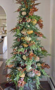 a christmas tree decorated with pumpkins and greenery