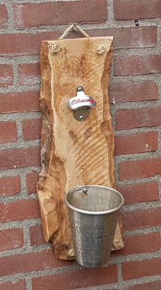 a metal bucket sitting on top of a piece of wood next to a brick wall