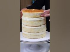 a stack of pancakes on a plate being held by a person with their hands over the top