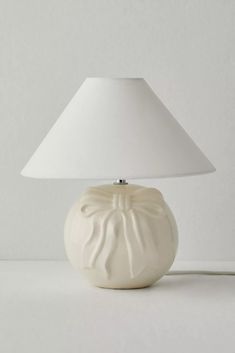 a table lamp with a white shade on the base and a light bulb attached to it