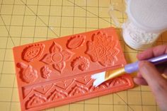 a person is using a paintbrush to decorate a plastic mold