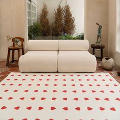 a living room with a white couch and red hearts on the rug in front of it